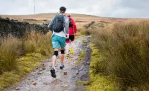 Runner wearing knee support while trail running on a rocky off-road path