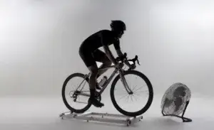 Cyclist performing Tabata intervals on indoor rollers with cooling fan for recover