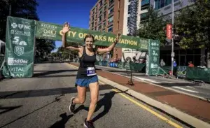 Runner finishing the City of Oaks Marathon with arms raised after hitting a 330 marathon pace goal.