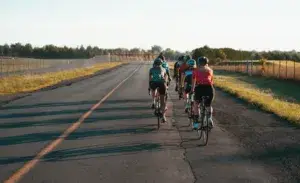 Group of cyclists riding on open road using cycling pacing calculator strategies.