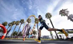 Athlete running at IRONMAN 70.3 Geelong with ferris wheel and palm trees in the background
