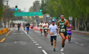 Runners executing negative split pacing during a marathon race on a city street.
