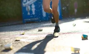 Runner passing water station during sub 3 hour marathon training with discarded cups on the road.