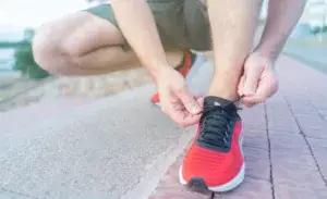 Runner tying shoelaces on red running shoes before starting a virtual marathon