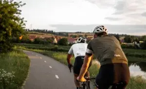 Two cyclists riding on a paved country road at sunset, illustrating typical cycling speed during a recreational ride