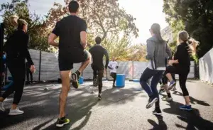 Group of athletes performing dynamic warm-up exercises before a running event, demonstrating the importance of using a warm-up calculator for optimal performance.