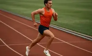 00m runner wearing track spikes mid-stride on outdoor track.