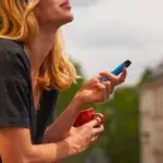 Woman vaping on a balcony with coffee cup – does vaping affect cardio health.