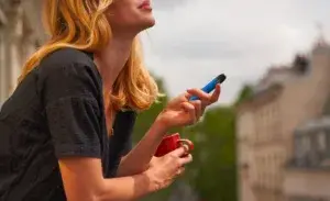 Woman vaping on a balcony with coffee cup – does vaping affect cardio health.