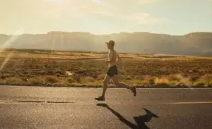 Runner training for a half marathon with time chart strategy in desert sunrise.