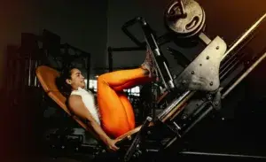woman using leg press machine in gym for leg press weight chart reference.