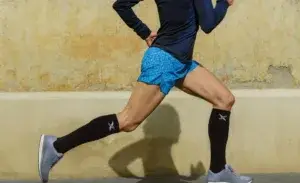 Runner wearing shin splints support socks during a mid-stride outdoor workout.