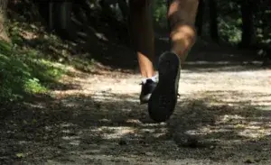 Runner experiencing ankle pain when running on a forest trail.