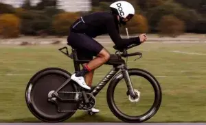 Triathlete riding a time trial bike equipped with the best crankset for triathlons on a flat course