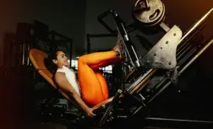 Woman performing leg press exercise in gym – hack squat vs leg press comparison.