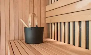 Wooden sauna bench with water bucket – how long should you be in a sauna athlete