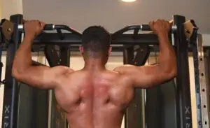Man using machines for back exercises to strengthen upper back and lat muscles during a gym workout.