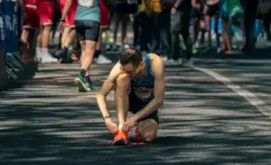 Runner tying shoes before race while managing runner’s stomach symptoms