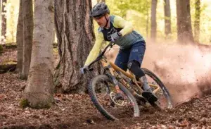 Strength training for mountain biking – rider cornering through forest trail with power and control.