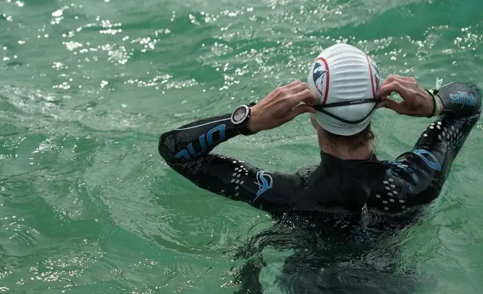 Vertigo after swimming in open water athlete adjusting swim cap