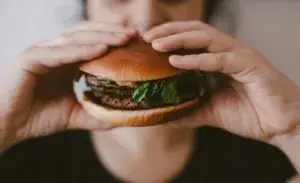 Runner enjoying a burger after training – illustrating the question can runners eat whatever they want.