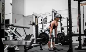 Athlete performing barbell deadlift in gym as part of strength plan to improve cycling performance through squats