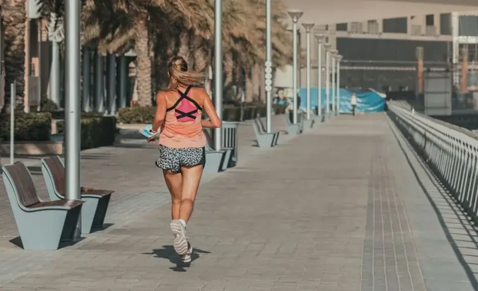 Runner performing fartlek training examples along an urban waterfront lined with palm trees.