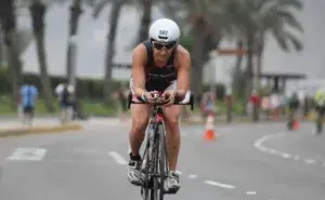 Triathlete cycling during the bike leg of an Ironman race, training to finish within the Full Ironman Cut Off Times.
