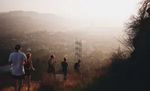 Group of runners doing hill running at sunset overlooking city and mountains