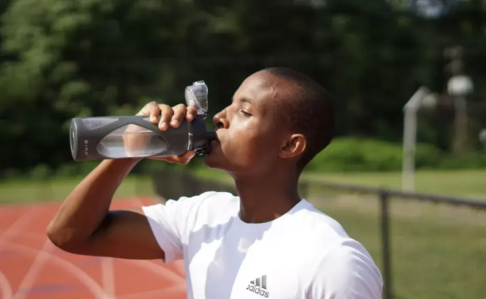 Runner carrying water during training on a track
