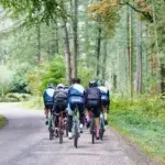 Group of cyclists on a forest road illustrating how many kilometers of cycling is equal to running