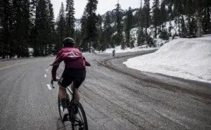 Cyclist riding uphill in snowy mountains – is cycling good for lower back pain