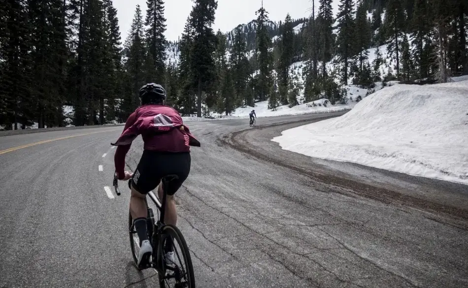 Cyclist riding uphill in snowy mountains – is cycling good for lower back pain