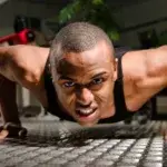 Man performing Navy Seal burpees with intense focus in the gym.