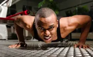 Man performing Navy Seal burpees with intense focus in the gym.