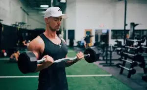 Athlete performing barbell curls during a brachialis muscle workout in the gym