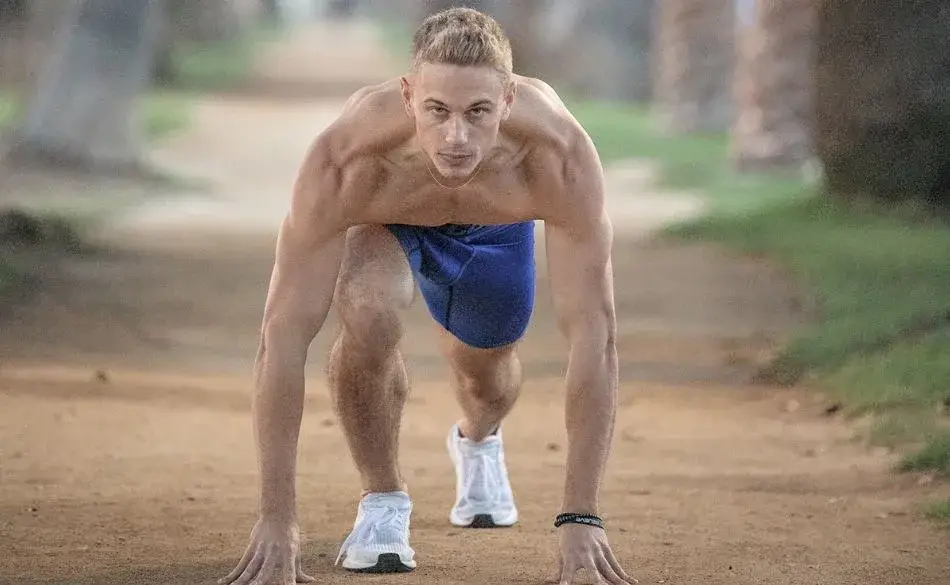 Runner preparing to sprint on a trail, showing lean strength and focus. - can runners build muscle?