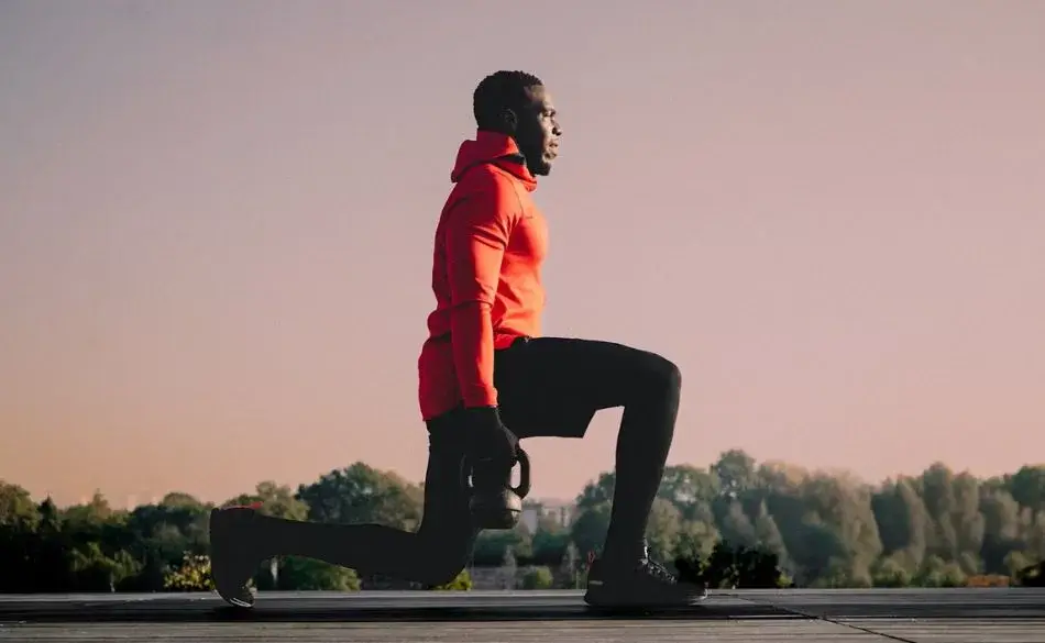 Athlete doing lunges with kettlebell as part of exercising twice a day routine