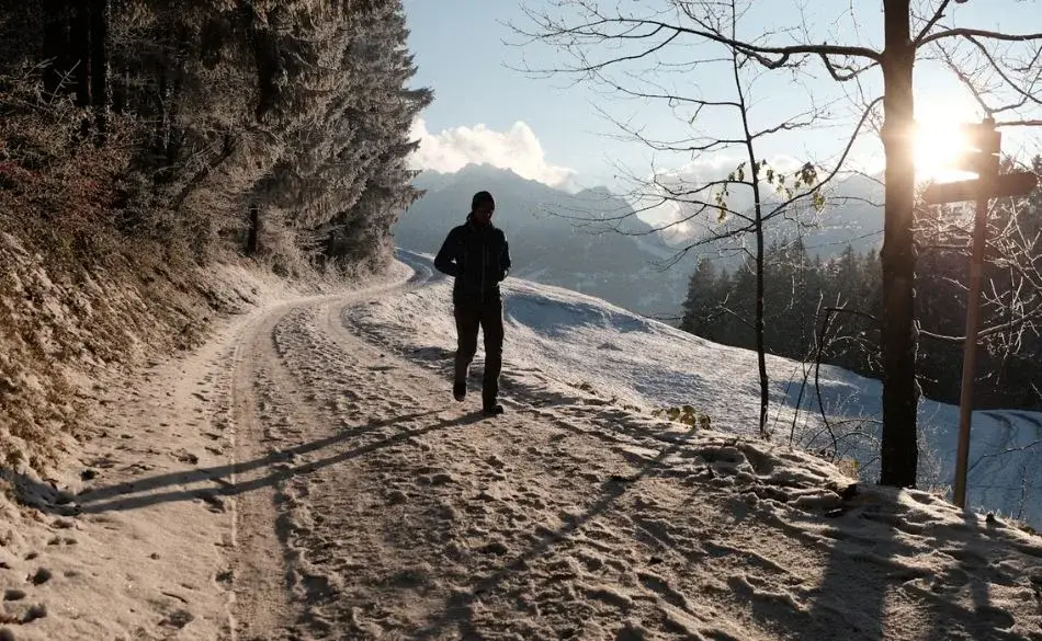 Runner on a snowy mountain trail during sunrise running in snow
