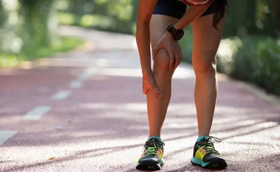 Runner holding shin during workout on track needing shin splint exercises for relief