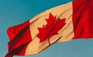 Canadian flag waving under a clear blue sky symbolizing the spirit of the best marathons in Canada