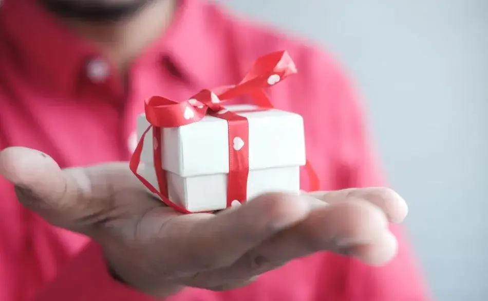 Close-up of a person holding a small gift box with a red ribbon — perfect representation of thoughtful gifts for triathletes