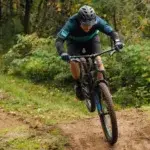 Mountain biker training on a forest trail showing the fitness side of MTB vs road cycling