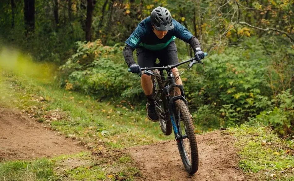 Mountain biker training on a forest trail showing the fitness side of MTB vs road cycling