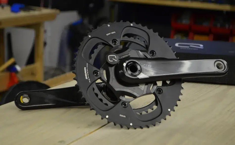 Close-up of a power meter on bike crankset showing detailed chainrings and sensors for accurate cycling power measurement