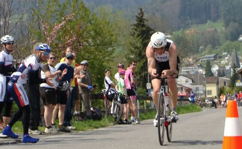 Athlete racing on a bike during a run cycle run duathlon event with spectators cheering