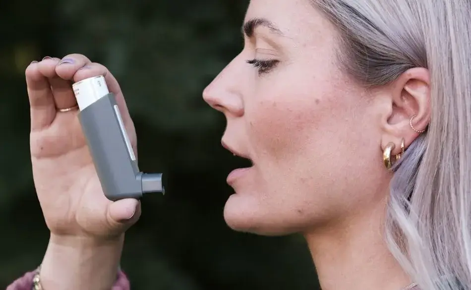 Woman using an inhaler before running with asthma