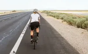 Cyclist experiencing shin pain while cycling on a countryside road, illustrating cycling with shin splints