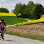 Cyclist riding on a quiet country road showing how many hours per week should I train cycling