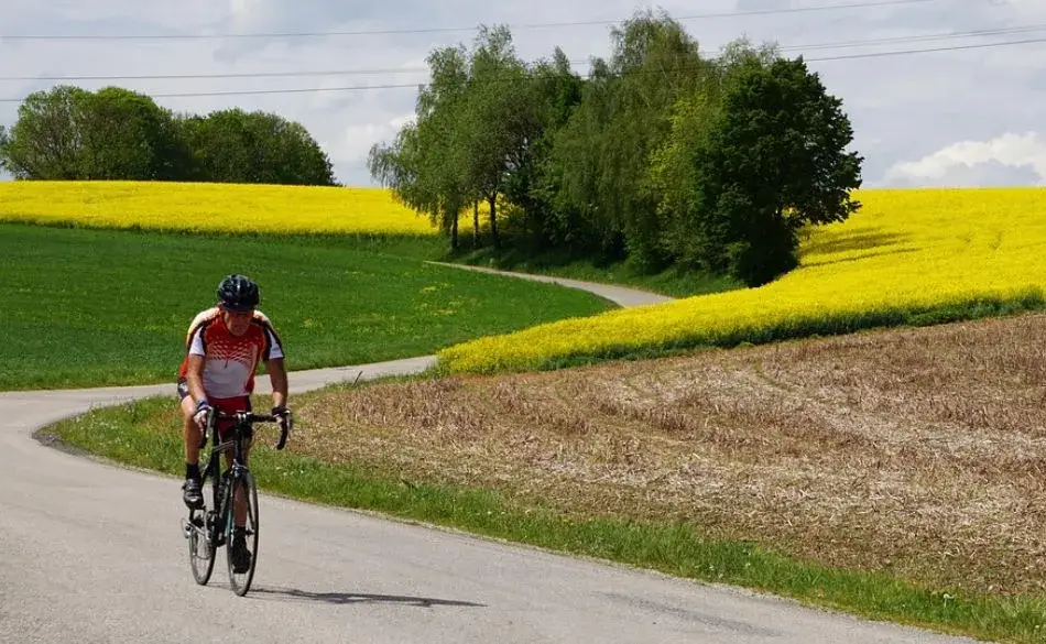 Cyclist riding on a quiet country road showing how many hours per week should I train cycling